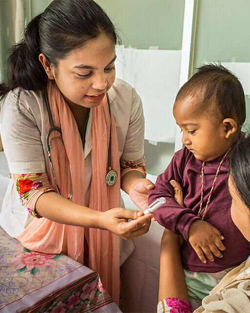 Mother with her child in the treatment room of Prof. Dr. Moazzem Hossain's General Hospital and Specialty Clinic.