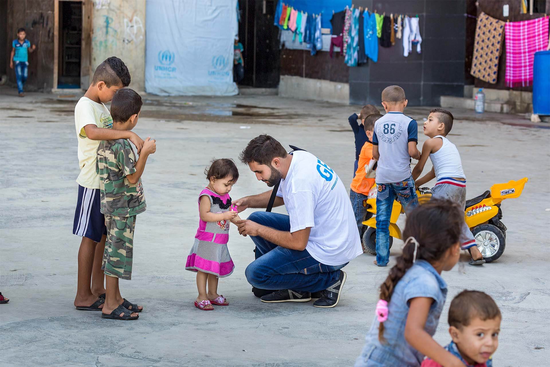 Addullah Nimje (Mitte, Cap Anamur Krankenpfleger) im Gespräch mit einer kleinen Patientin im Innenhof des „Settlement“ Hochhaus in Sidon. Hier leben circa 200 syrische Bürgerkriegs-Flüchtlingfamilien (circa 1.200 Menschen) unter schwierigsten Bedingungen.