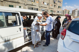 Transport der Patient:innen mit dem Cap Anamur-Bus. Addullah Nimje (Mitte, Cap Anamur Krankenpfleger) hilft beim Ausstieg.