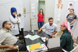 Untersuchungszimmer: (links, Dr. Dr. Ali Jouni (Healthstation), Krankenschwester und Mitarbeiterinnen der Healthstation, Addullah Nimje (Mitte, Cap Anamur Krankenpfleger) im Gespräch mit einem Patienten (syrischer Bürgerkriegs-Flüchtling) in der Healthstation in Sidon.