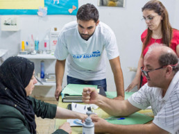 Examination room (from right, Dr. Ousama Dimassi (Healthstation), Healthstation staff member, Addullah Nimje (Cap Anamur nurse) talking to a patient (Syrian civil war refugee) at the Healthstation in Sidon.