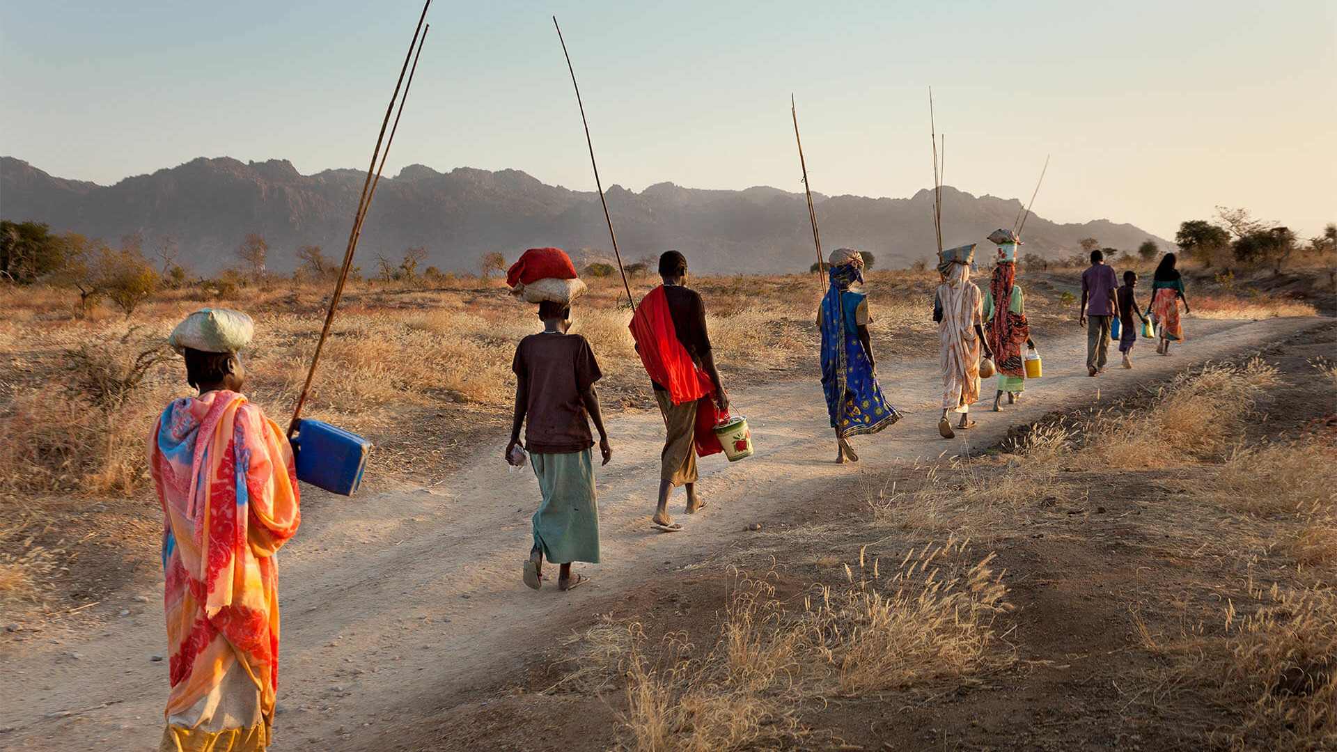 Kampf um Freiheit – Der vergessene Krieg in den Nubabergen. Frauen bei Kauda auf dem Rueckweg in ihr Dorf. Mit den Stangen werden Grashuepfer gefangen.